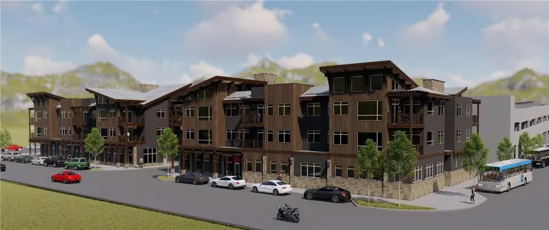 Modern three-story mixed-use building with large windows, balconies, and wood accents; cars, a motorcycle, and a bus are parked along the street; mountains and blue sky are in the background.