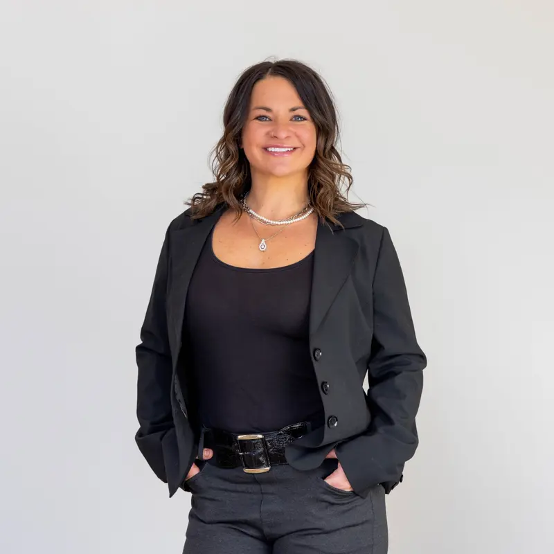 Jennifer Luberto smiling in a black blazer against a light studio background